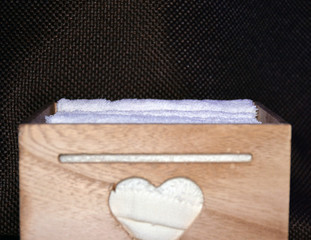 Wooden box for white towels. Face towel. Skin care. White towels in a wooden box on a brown background.