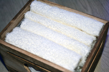 Wooden box for white towels. Face towel. Skin care. White towels in a wooden box on a brown background.