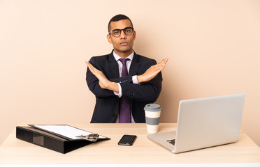 Young business man in his office with a laptop and other documents making NO gesture