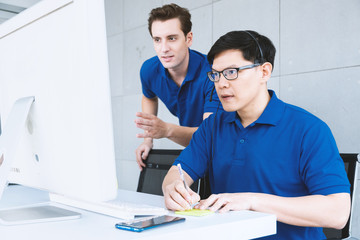 Focused businessman telemarketer agent wear headset make conference video call and take note while online client in computer with manager help and advice. Operator work in customer care support office