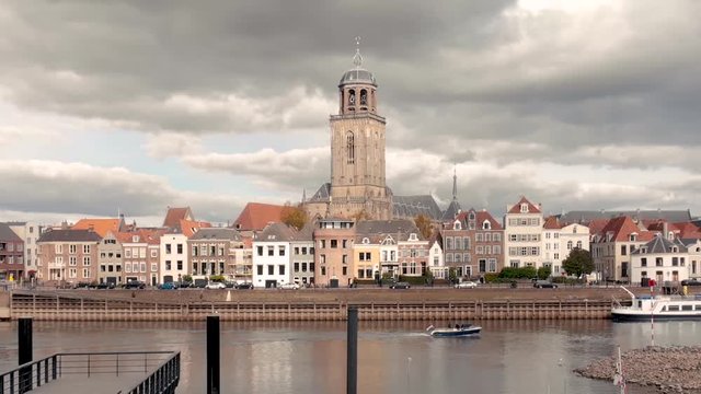 Aerial cityscape with parallax effect of the Deventer city facade seen from the river IJssel in The Netherlands against a dramatic afternoon cloudy sky with boat passing by
