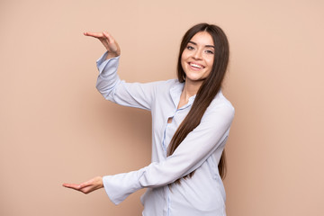 Young woman over isolated background holding copyspace to insert an ad