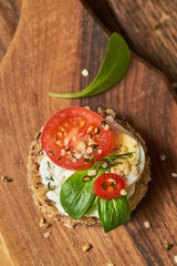 Healthy round sandwich with cottage cheese, egg and tomato on a wooden board. Healthy eating concept. Toast sprinkled with seeds. 