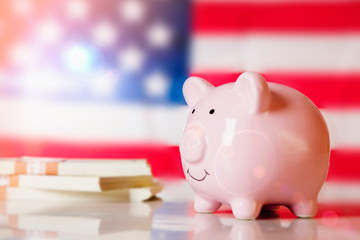 Piggy bank and money in front of US flag as symbol of economy of the United States of America.