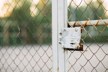 Panoramic view of the fence grid with a lock with a sports field behind