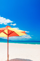 Empty white sand beach and parasol, blue sky