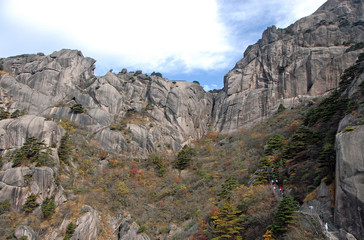 Fototapeta na wymiar Huangshan Mountain in Anhui Province, China. View of Narrow Cliff between Turtle Peak and Lotus Peak with walkers on the steep paths of Huangshan. Scenic view of walking on Huangshan Mountain, China.