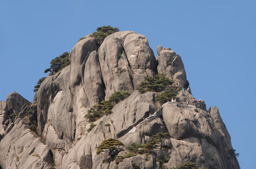 Huangshan Mountain in Anhui Province, China. Close up of the summit of Lotus Peak, the highest point of Huangshan. Scenic view of the cliffs, pine trees and summit path on Huangshan Mountain, China.