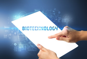 Hand holdig futuristic tablet with BIOTECHNOLOGY inscription, new technology concept