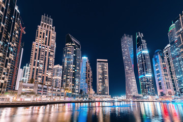 Fototapeta na wymiar Night colorful view of the famous tourist attraction of the city of Dubai - Marina seaport and illuminated skyscrapers. Travel and real estate in United Arab Emirates