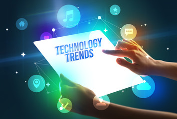 Holding futuristic tablet with TECHNOLOGY TRENDS inscription, new technology concept