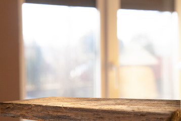 An empty wooden tabletop on a window pane and abstract green blur from the garden with a view of the yard, can be used to display or assemble your products (or products).