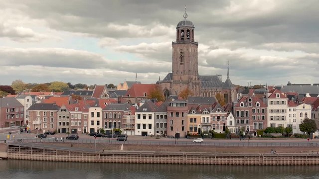 Aerial parallax effect showing the Dutch medieval city of Deventer with cars passing on the boulevard at the river IJssel and soft dramatic clouds closing in