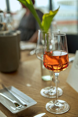 A glass filled with rose wine is on the nicely arranged table. Concept: decoration or food and drink