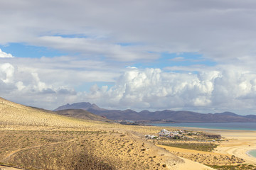 Panoramic view at sandy beach of Risco del Paso on canary island Fuerteventura with  turquoise water and mountain range in the background