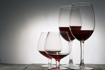 Glasses with red dry wine. Stand on wooden boards. Shot in backlight.