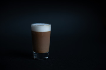 mini cup of cappuccino in a glass cup on black background