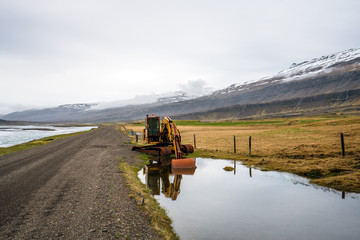 Naklejka premium Old and rusty excavator by the side of a gravel road and the river Hamarsa. From Hamarsdalur near Bragdavellir in east Iceland. Travel and landscape concept.