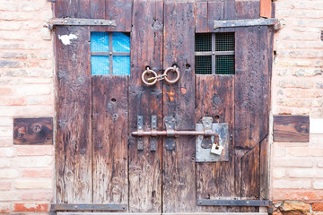Old ancient wooden double door with old locks and a handle on the streets of Bergamo, Italy
