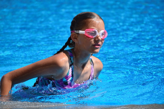 Cute girl enjoys in swimming pool at the hotel.  teenager at resort in water. swimming training. Holidays with children at sea.