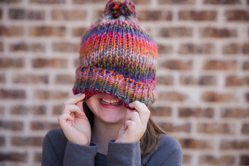 Young girl wearing winter hat over face