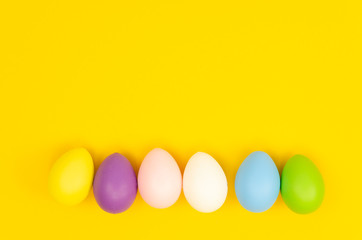 Set of colorful Easter chicken eggs on a yellow background. Flat lay with space for text