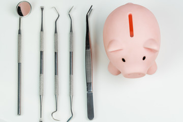 piggy bank with dentist tools isolated on white background