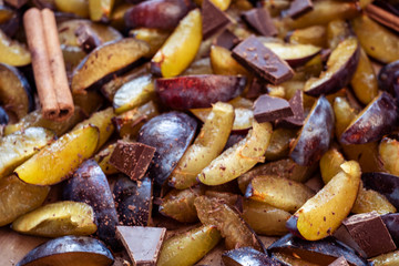 Fresh plum fruit cut into slices, slices with cinnamon sticks, chocolate, cloves. Preparation of ingredients and fruits for making delicious jam.