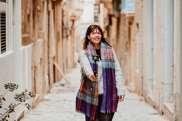 .Young female tourist touring Valletta, capital of Malta. Travelling with a compact camera to broadcast her trip on social networks. Lifestyle