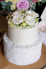 Two-tiered white wedding cake decorated with  flowers