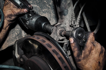 Mecánico reparando la transmisión y los frenos de un automóvil en el taller.
