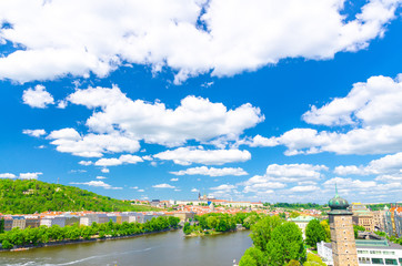 Aerial panoramic view of Prague city, historical center with Prague Castle, St. Vitus Cathedral, Hradcany district, green hills, Vltava river, blue sky white clouds background, Bohemia, Czech Republic © Aliaksandr