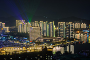 Night view of Sanya city with bright multi-colored illumination buildings, structures, roads, sidewalks, poles, bridges.