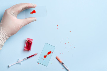 lab technician dripping human red blood on slide glass for virus test on blue background