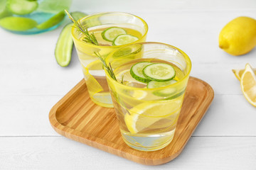 Glasses of cold cucumber water on white table