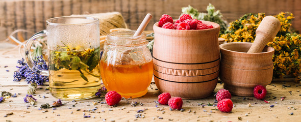 Herbal tea, honey and raspberries on a wooden table, alternative medicine, Ayurveda, dried flowers