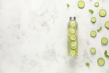 Bottle of cold cucumber water on white background