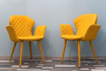 Two empty yellow chairs over blue wall background.