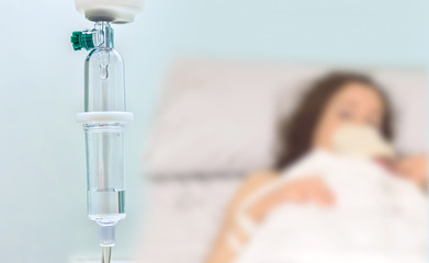 Closeup shot of medicine in an iv drip and a patient in the hospital