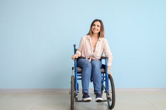 Handicapped young woman in wheelchair near color wall