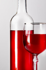 Bottle and glass of red wine on the table on a dark background.
