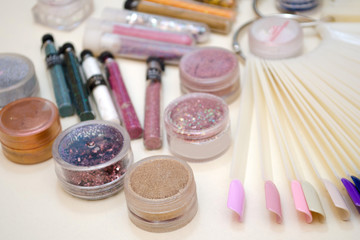 Obraz na płótnie Canvas Jars with sparkles and decor for nail design, color samples of gel polish on a plastic tips closeup