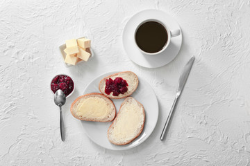 Tasty bread with butter, jam and coffee on white background