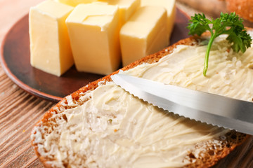 Spreading of tasty butter on slice of bread, closeup
