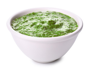 Bowl with tasty pesto sauce on white background