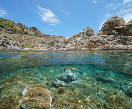 Spain Mediterranean sea, rocky cove with tourists in summer in the Cap de Creus, split view over and under water surface, Costa Brava, Catalonia, Cala Culip