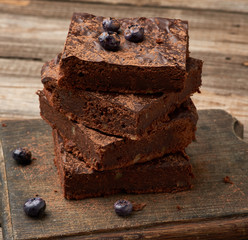 stack of square baked slices of brownie chocolate cake with walnuts