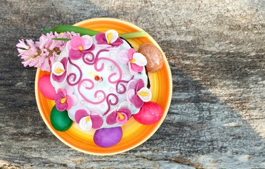 Easter cake with a candle, painted eggs, spring flowers. Easter composition on the old wooden table, top view.