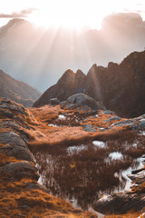Sun rays passing through high mountains with illuminated peaks and stones. Beautiful landscape in Val Nambrone, Trentino, Italy
