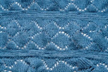 Knitting from thick soft yarn of blue color. Fragment close-up. Textile background.